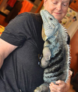 Elaine holding a large blue-green iguana.