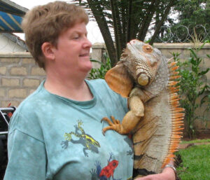 Elaine holding a large grayish iguana with orange spines down it's back.