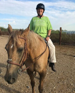 Elaine riding bareback on a tan horse.