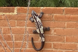 a Tan and brown metal lizard mounted to a brick wall.