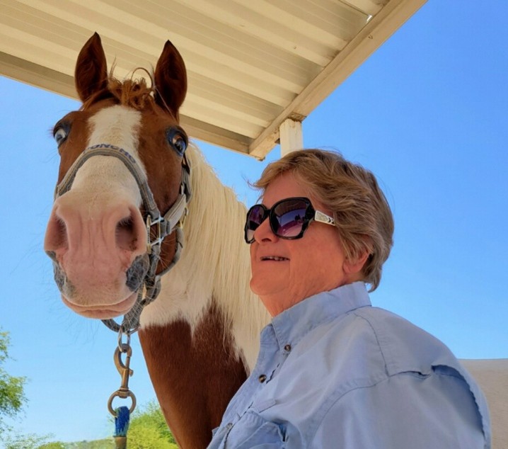 Elaine holding the lead to her tan and white horse. 